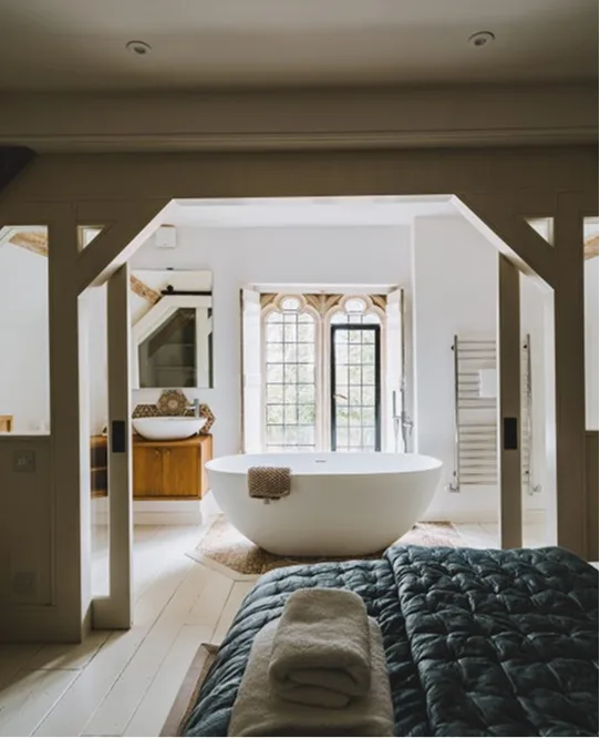 A bedroom with a freestanding bath beneath leaded windows
