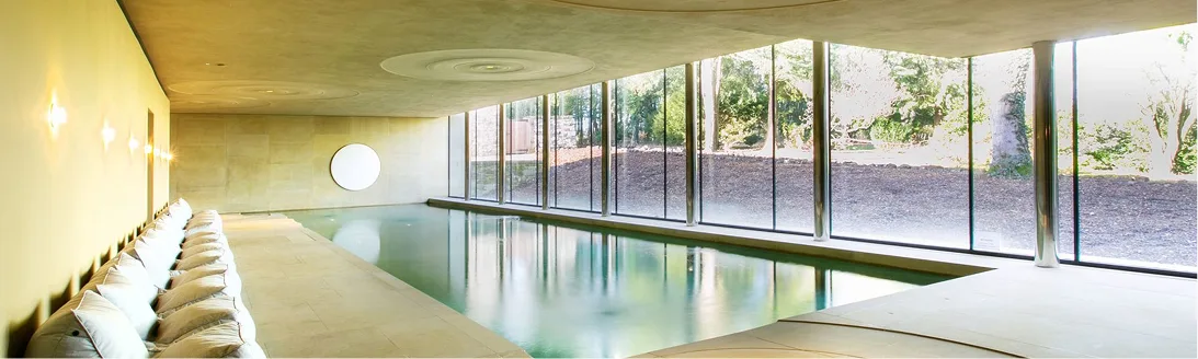 The indoor pool with a wall of glass onto the grounds