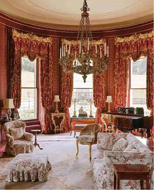 An ornate drawing room with a chandelier and bay windows