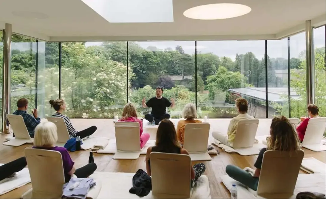 A meditation session in the glass-walled studio overlooking the gardens